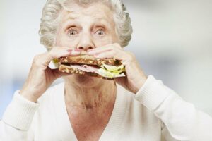 Idosa comendo sanduiche Artigo Obesidade na 3a idade