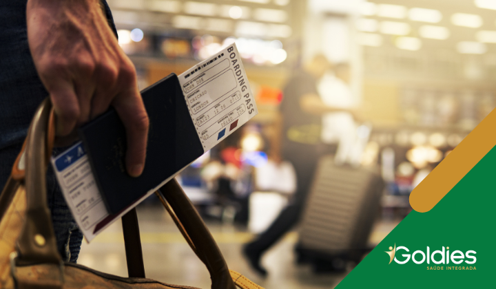 Close na mão de um viajante que segura uma passagem em um terminal de viagens, ilustrando o post "Dicas para viajar com segurança na Terceira Idade"